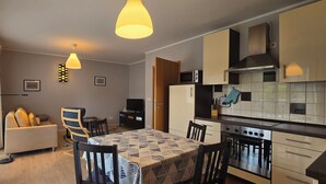 Cocina compacta con comedor, sofá y vistas a través de un ventanal.