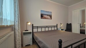 Un dormitorio con cama, mesitas de noche, escritorio, silla y armario.