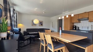 Eine moderne Küche mit Holzschränken, einem Edelstahl-Geschirrspüler und einem Essbereich mit Holztisch und -stühlen.