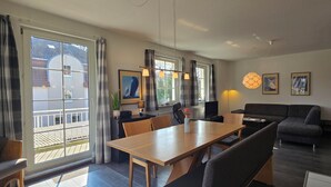 Ein modernes Wohnzimmer mit Essbereich, großen Fenstern und Blick ins Freie.