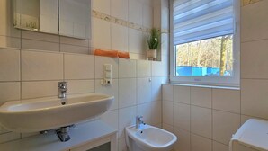 Une salle de bain avec un lavabo, des toilettes et une fenêtre.