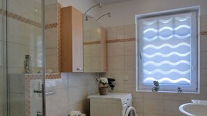 A compact bathroom with a toilet, washing machine, and sink. - Zentrale 2 Zimmer-fewo für 4 Pers., Terrasse mit Strandkorb (Graal-Müritz)