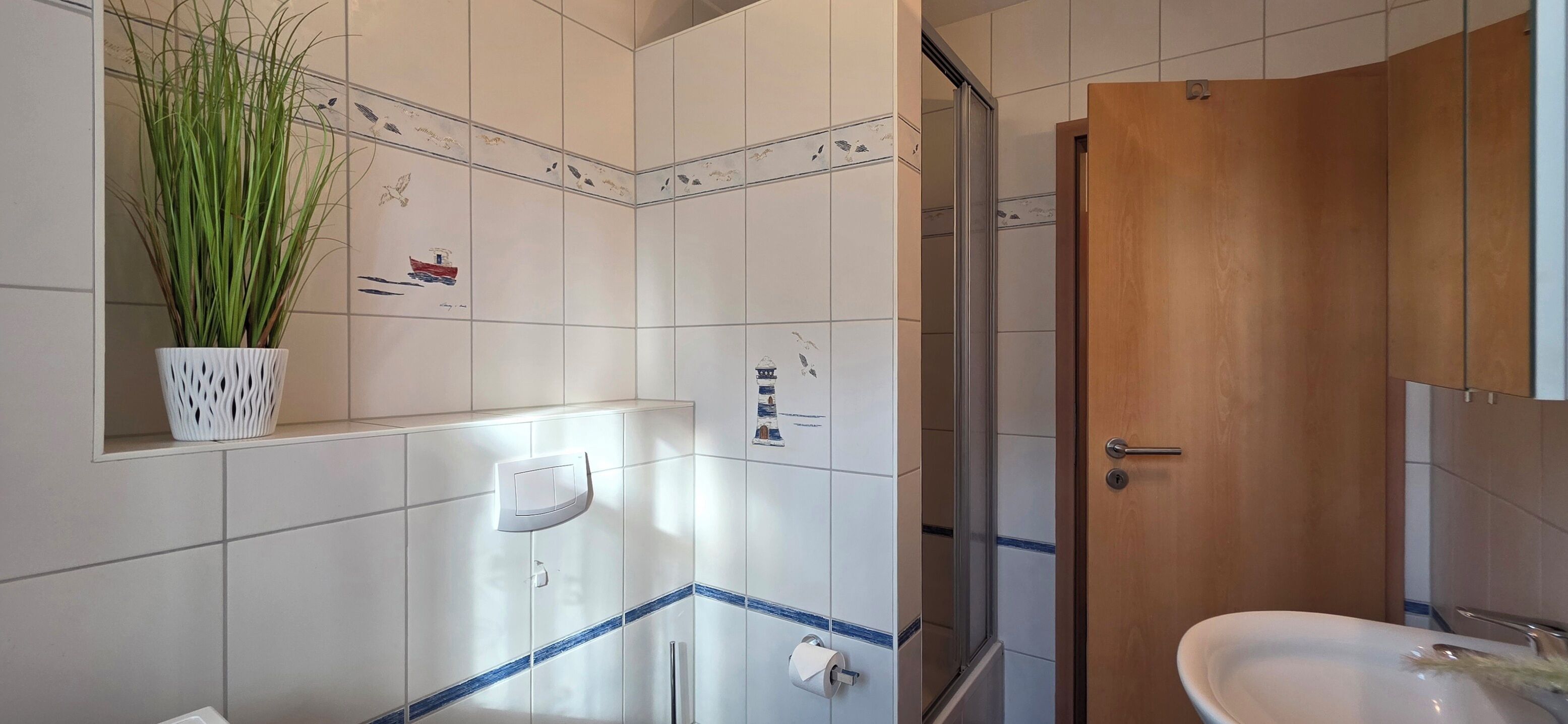 Une salle de bain avec des carreaux blancs, une porte en bois, un lavabo et une douche.