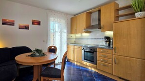 Una cocina compacta con armarios de madera, estufa y comedor con mesa y sillas.