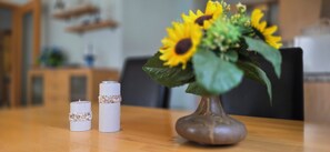 A table with a vase of sunflowers, two candles, and a decorative item. - 2-zi.-fewo im 1. OG für 3 Pers., Ca.50 m² mit Wlan (Graal-Müritz)