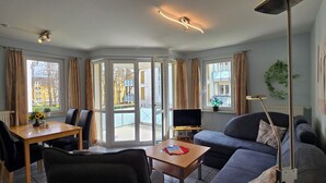 Un salon comprenant un canapé, une table basse, un téléviseur et un coin repas avec des chaises et une table.