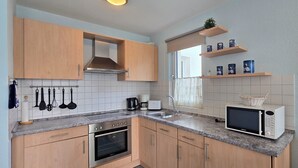 Une cuisine moderne avec des meubles en bois, un four encastré, un four à micro-ondes et une machine à café.