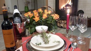 A dining table set with a white plate, cutlery, wine bottles, glasses, and a candle. - Luxuriöse 3-zi.-fewo für 4 Pers., Inklusive Bettwäsche, Handtücher und Wlan (Graal-Müritz)