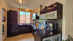 A modern kitchen with dark cabinetry, a built-in oven, and a coffee machine. - Luxuriöse 3-zi.-fewo für 4 Pers., Inklusive Bettwäsche, Handtücher und Wlan (Graal-Müritz)