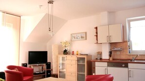 Un espacio habitable compacto con comedor, kitchenette y televisor.