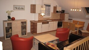 Una cocina compacta con armarios de madera, un comedor con sillas rojas y una pequeña mesa.