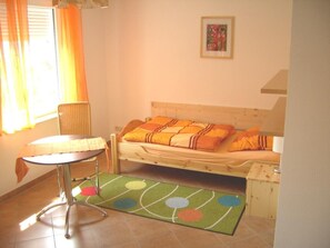 A small, cozy bedroom with a single bed, a side table, and a window with curtains. - Große 3 Zi.-maisonette-fewo für 5 Personen, nur 700 m bis zum Strand (Graal-Müritz)