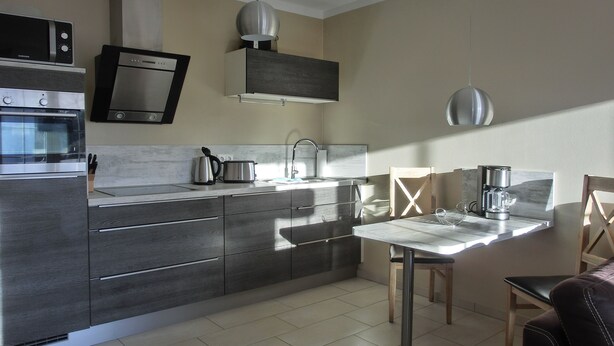 A modern kitchen with stainless steel appliances, a dining table, and a chair.