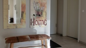 A modern interior with a bench, a wall-mounted mirror, and a decorative sign with the words "Welcome to Home".