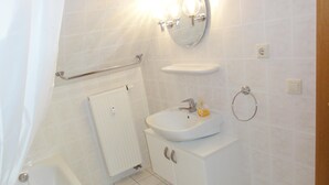 A bathroom with a bathtub, a sink, a mirror, and a towel rack.