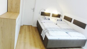 A bedroom with a bed, bedside tables, and a wooden bench.