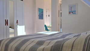 Ein Schlafzimmer mit Bett, Kleiderschrank, Stuhl und kleinem Tisch.
