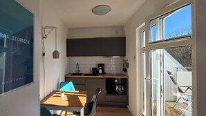 Eine kleine Küche mit einem Holztisch und Stühlen, einem eingebauten Backofen und einem großen Fenster.