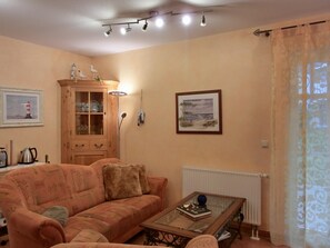 Un salon avec un canapé, une table basse en verre, un meuble et un tableau accroché au mur.
