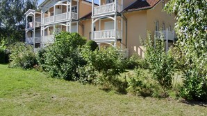 A two-story building with balconies, surrounded by greenery and a clear sky. - Strandnahe 3-zi-wohnung im Erdgeschoss mit Wlan (Graal-Müritz)