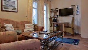 A living room with a sofa, a coffee table, a TV, and a bookshelf. - Strandnahe 3-zi-wohnung im Erdgeschoss mit Wlan (Graal-Müritz)