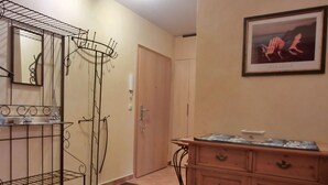 A hallway with a metal drying rack, a wooden cabinet, a door, and a framed picture on the wall. - Strandnahe 3-zi-wohnung im Erdgeschoss mit Wlan (Graal-Müritz)