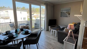 Una sala de estar moderna con comedor, ventanas amplias y vistas a edificios.