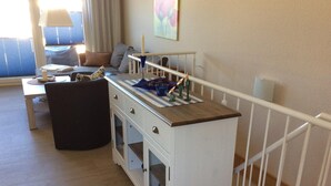A room with a kitchenette, a dining table, a sofa, and a window with curtains. - 3-zimmer-fewo mit 2 SZ für 4 Pers.wlan (Graal-Müritz)