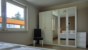 A bedroom with a bed, a chair, a wardrobe, and a window. - 3-zimmer-fewo mit 2 SZ für 4 Pers.wlan (Graal-Müritz)