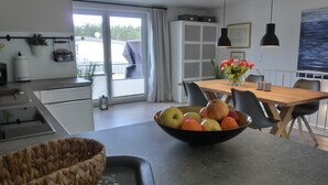 Eine moderne Küche mit Essbereich, einem großen Fenster und einer Obstschale auf dem Tisch.