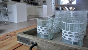 Eine moderne Küche mit weißen Schränken, einer Mikrowelle und einem Essbereich mit einer Bank. Auf einem Holztisch stehen dekorative Glasbehälter.