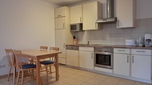 Una cocina compacta con mesa, sillas, microondas, estufa y cafetera.