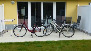 Ein gelbes Gebäude mit einer Terrassenfläche. Zwei Fahrräder stehen auf der Terrasse geparkt.