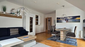 Un salon moderne comprenant un canapé, une table basse, une table à manger avec des chaises et un téléviseur.