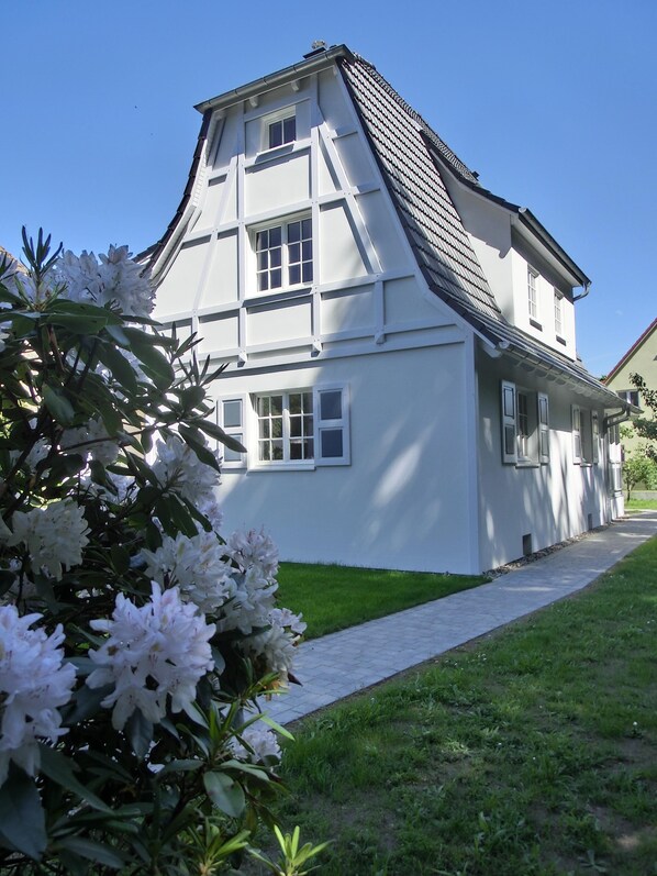 A two-story building with a steeply pitched roof and white exterior walls.