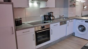 Een moderne keuken met witte kasten, roestvrijstalen apparatuur, een inbouwoven en een wasmachine.