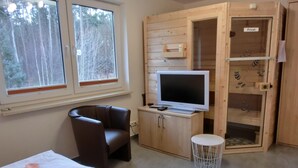 Een kamer met een bed, een stoel, een televisie en een houten kastje met een 'Privat' bordje.