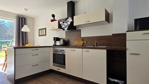 Eine moderne Küche mit weißen Schränken, einem eingebauten Ofen, einer Mikrowelle und einer Kaffeemaschine.