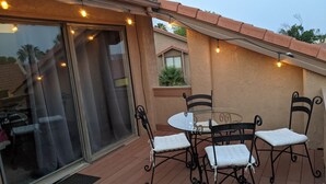 A patio with a glass door, a round table, and four chairs. - Spacious 1 Bedroom Condo With Cute Bonus Room (St. George)