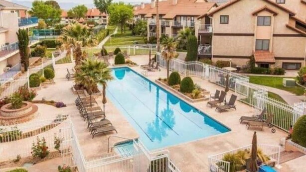 A residential area with a swimming pool, lounge chairs, and a fenced patio area. - Spacious 1 Bedroom Condo With Cute Bonus Room (St. George)
