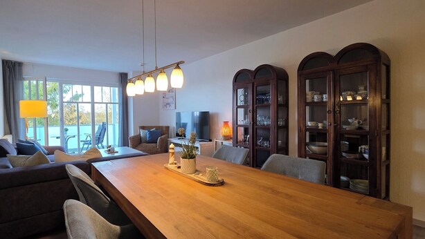 Un espace repas moderne avec une table en bois, des sièges rembourrés et un téléviseur.