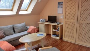 A cozy room with a sofa, a small table, a TV, and a bookshelf.