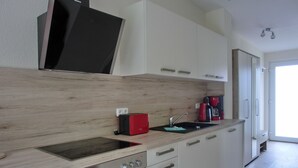 Une cuisine moderne avec un plan de travail en bois, un four encastré, un évier et une machine à café rouge.