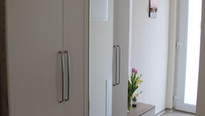 Une pièce comprenant une armoire, une petite table avec un vase et un miroir.