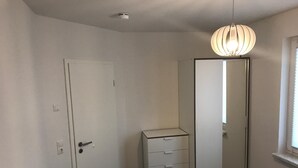 Et soveværelse med seng, kommode, spejl og loftslampe.