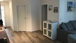 En moderne stue med en grå sofa, et lille hvidt skab og trægulv.