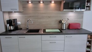 Eine moderne Küche mit Einbauofen, Kaffeemaschine, Toaster und Spüle.