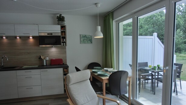 Eine moderne Küche mit Mikrowelle, Schränken und einem Essbereich mit Tisch und Stühlen.