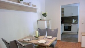 A dining area with a wooden table set for two, grey upholstered chairs, and a mirror above the table. - 2-room apartment for 3 people close to the beach (Graal-Müritz)