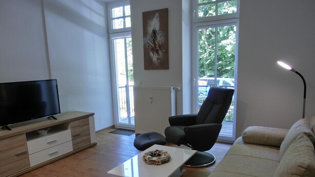 A living room with a flat-screen TV, a sofa, a chair, and a coffee table. - 2-room apartment for 3 people close to the beach (Graal-Müritz)